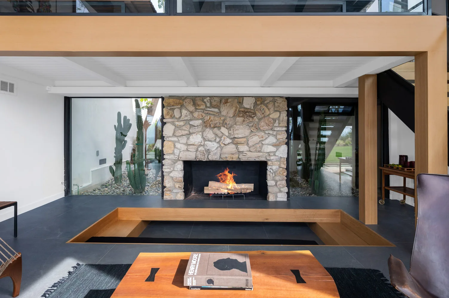 A lounge at 5901 Filaree Heights, Malibu: low seating by a fireplace under a timber ceiling.