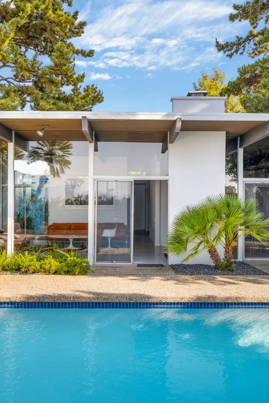 The Calvin House: wide eaves and glass walls over the pool, in afternoon light.