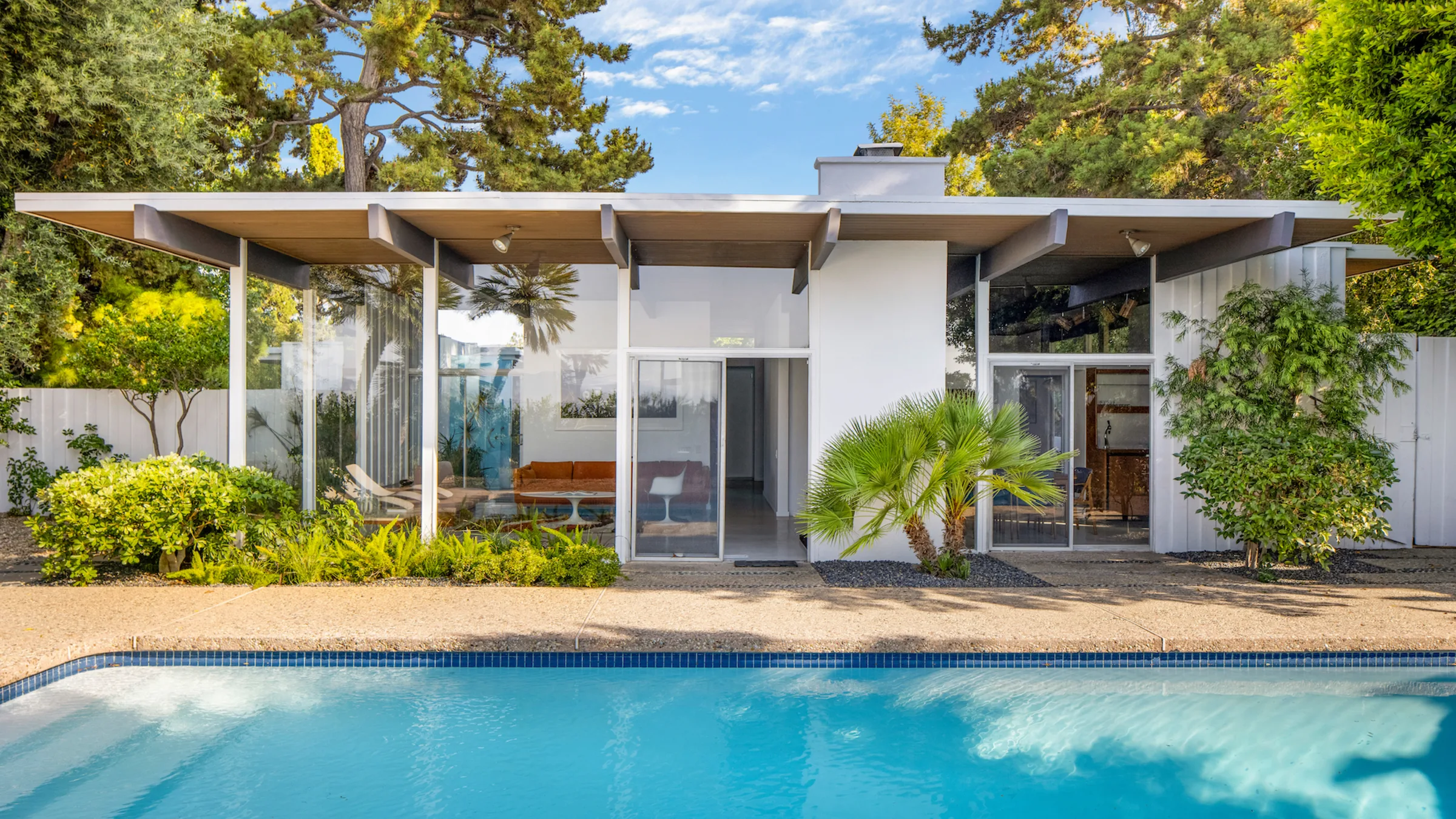 The Calvin House: wide eaves and glass walls over the pool, in afternoon light.