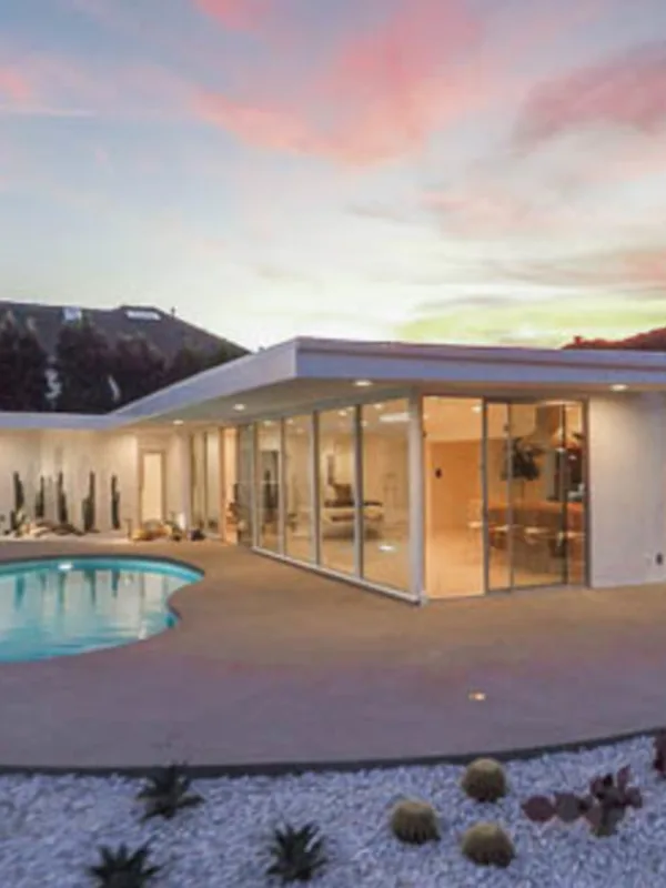 Casiano Road at twilight: the white pavilion glowing through its glass beside the pool, the sky fading over Bel Air.