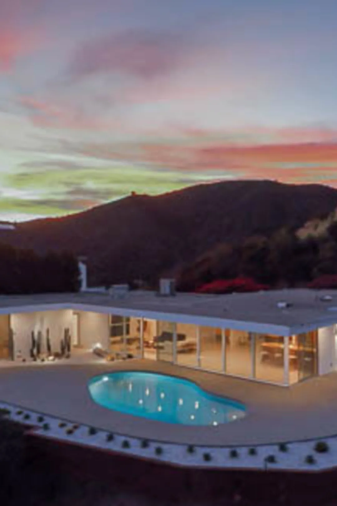Casiano Road at twilight: the white pavilion glowing through its glass beside the pool, the sky fading over Bel Air.