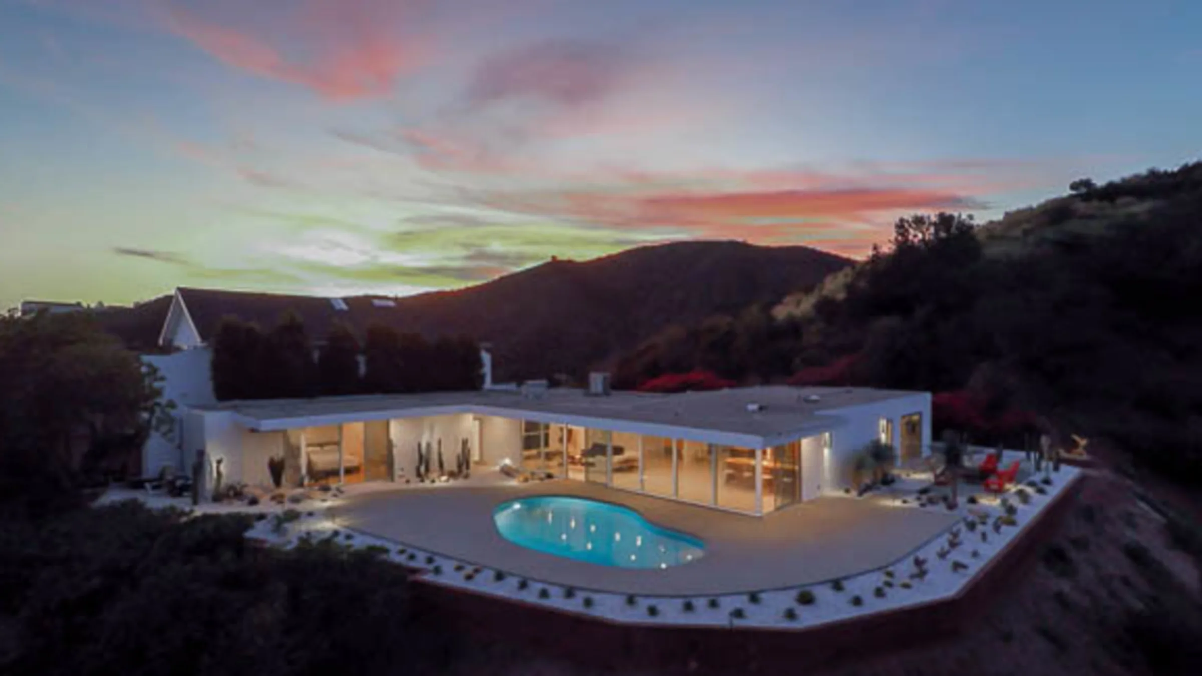 Casiano Road at twilight: the white pavilion glowing through its glass beside the pool, the sky fading over Bel Air.