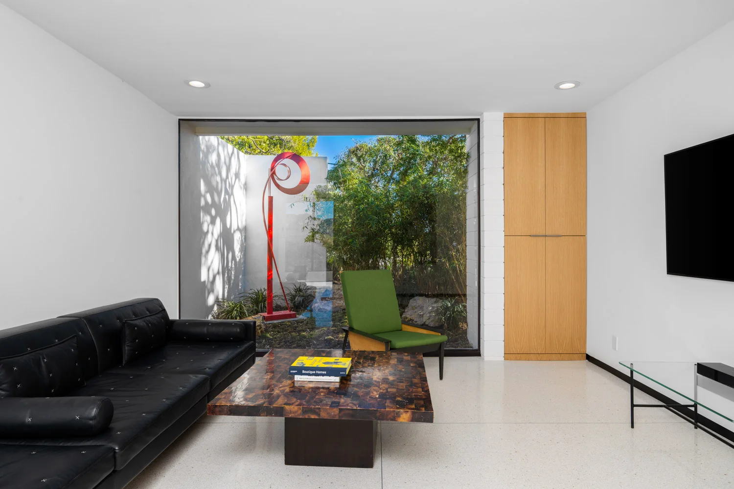 The media room: a black sofa and a red sculpture in the court.