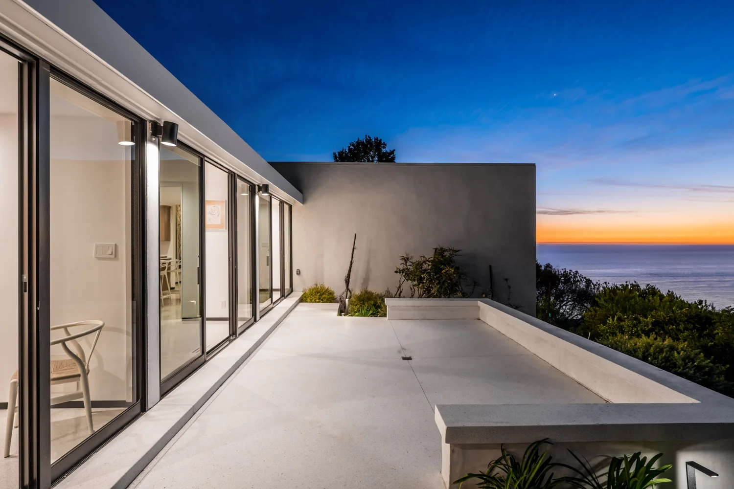 The patio at dusk, the ocean beyond the roof.