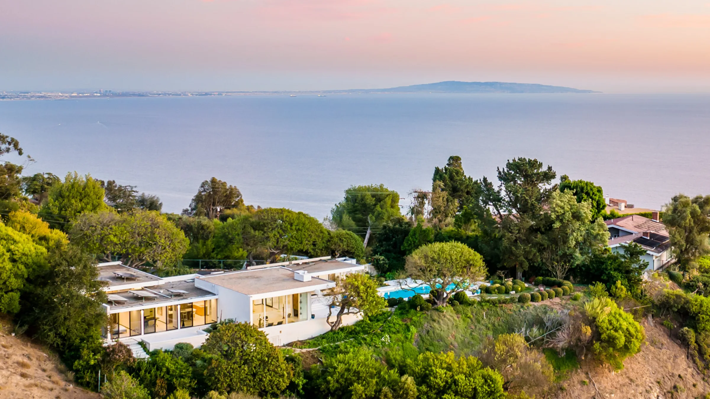 The Cool Oak House, Malibu, its walls of glass glowing at nightfall.