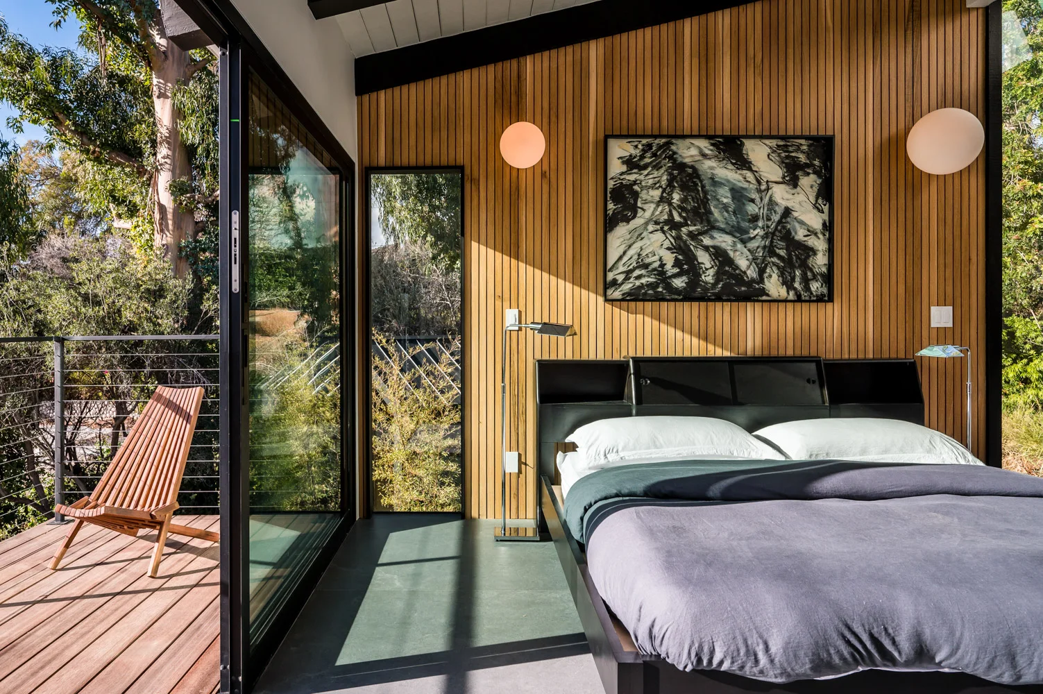 The main bedroom opening onto its balcony, slatted wood behind the bed.