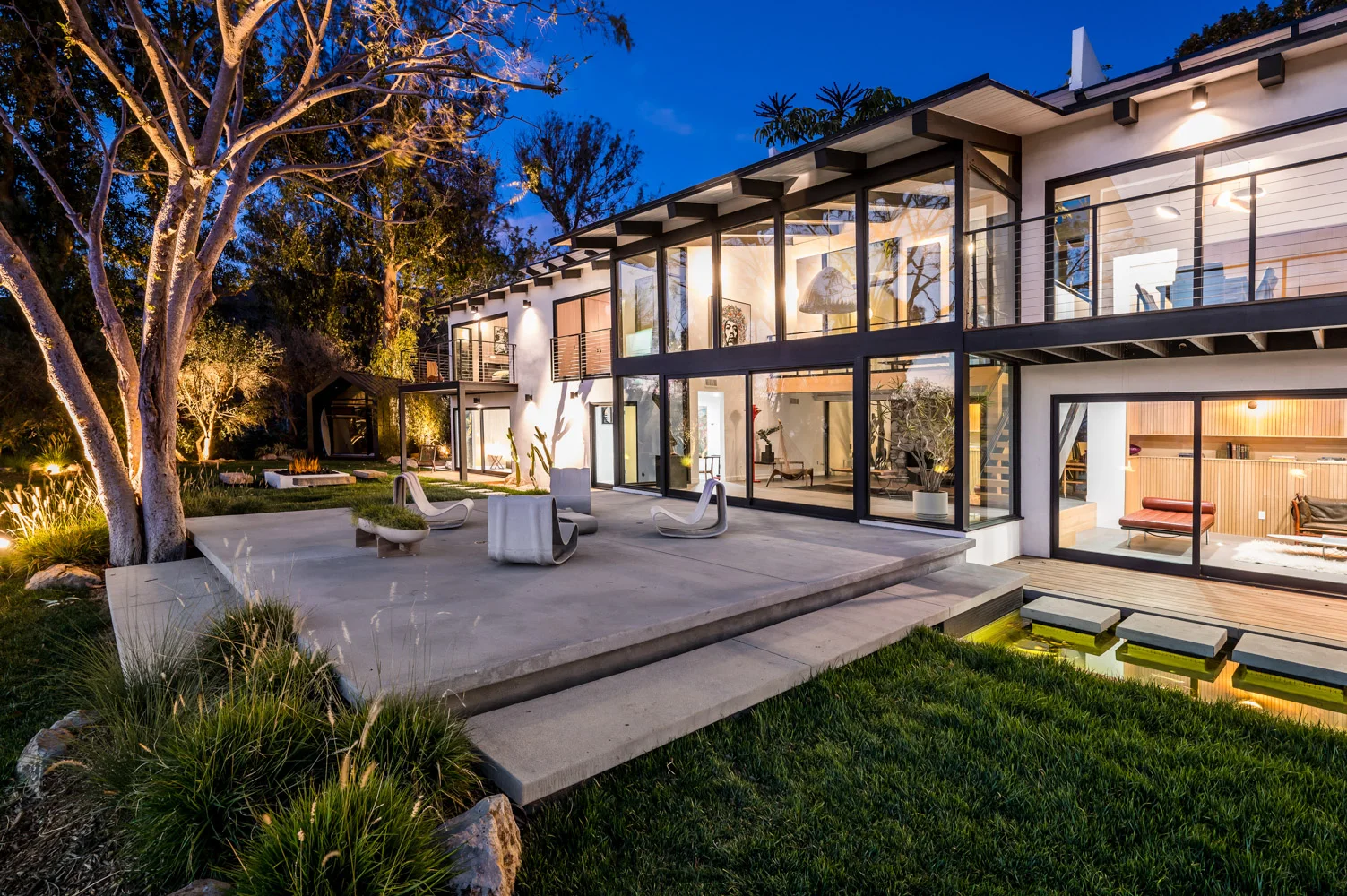 The house at night from the lawn, glowing through the glass.