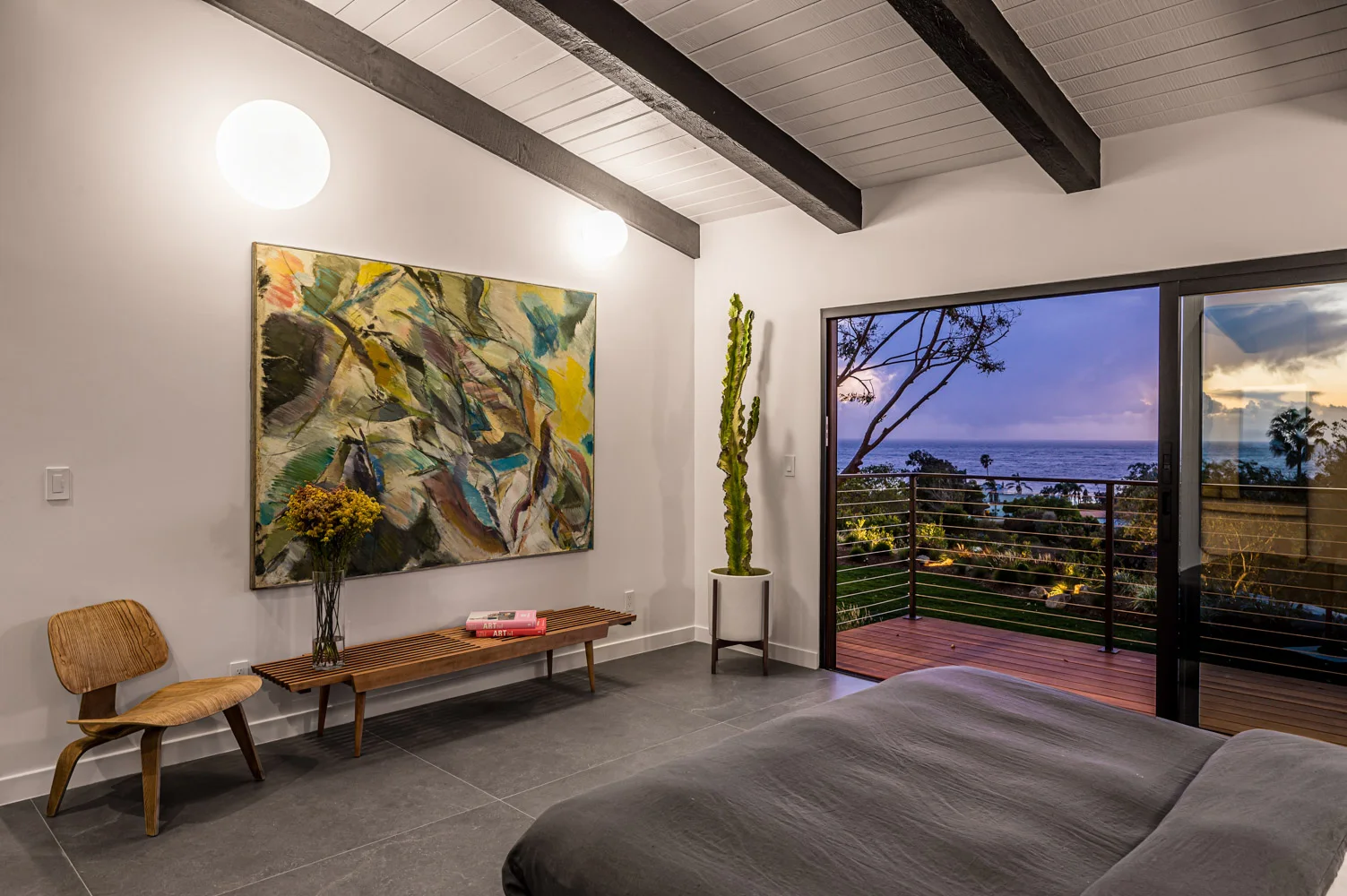 The main bedroom at night, its glass wall open to the lit garden.