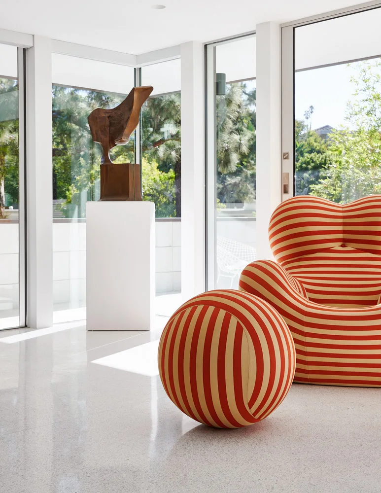 The sitting room: a striped red chair by the glass.