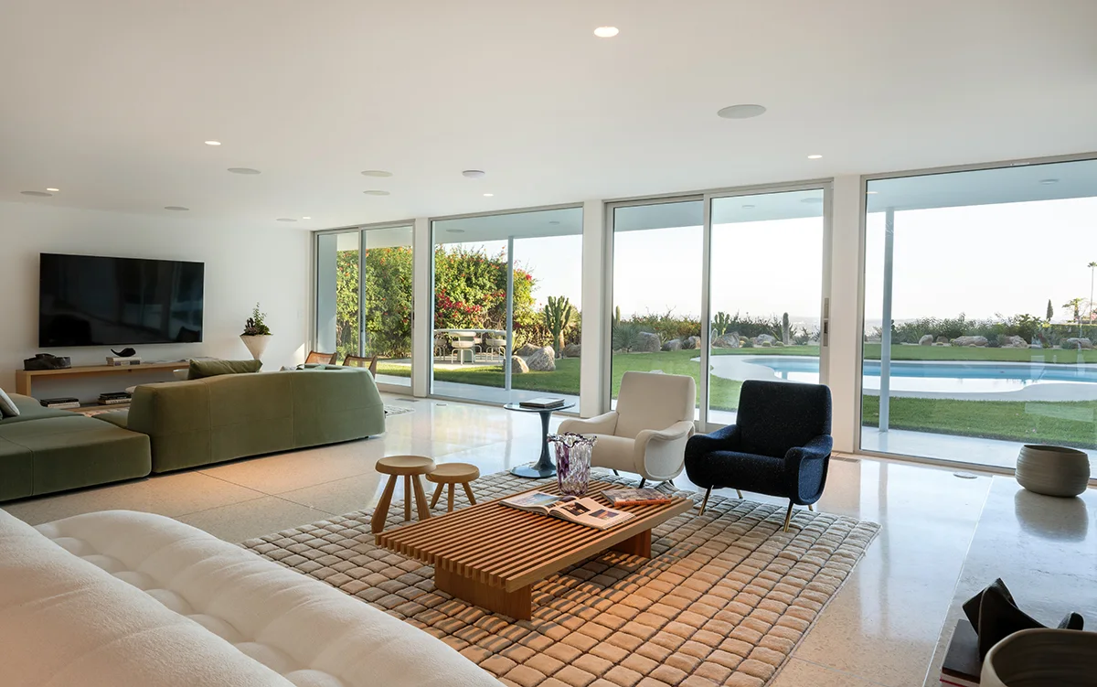 The kitchen: a white island, walnut cabinetry, cactus in the court beyond.