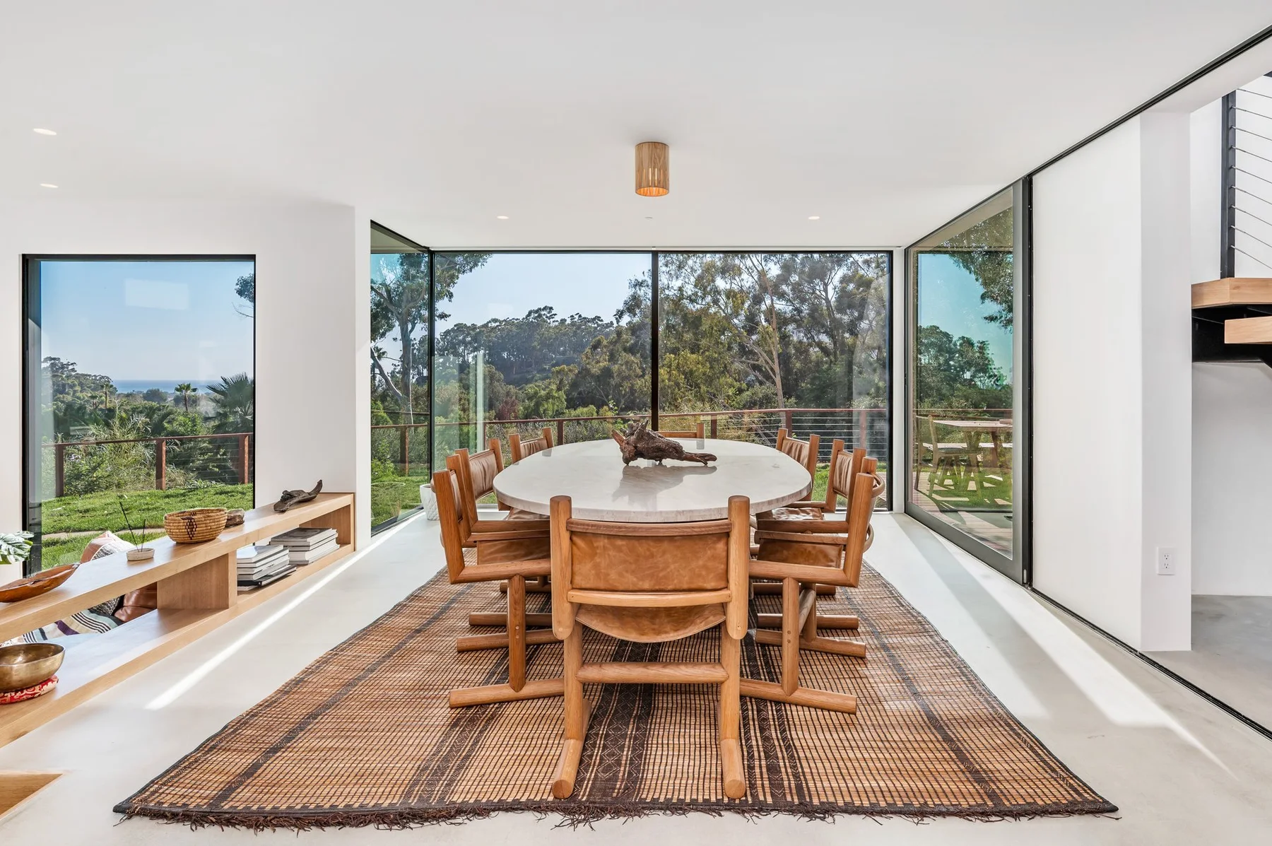 The dining room, a live-edge table and the hillside in the glass.