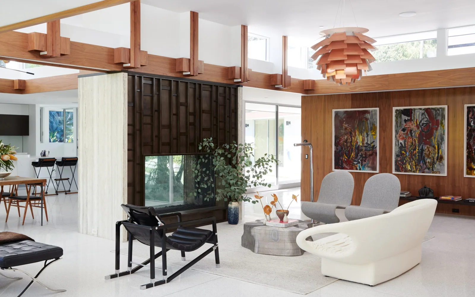 The living room at 1061 Loma Vista, Beverly Hills, installed: sculptural seating, art and a pendant light under the timber ceiling.