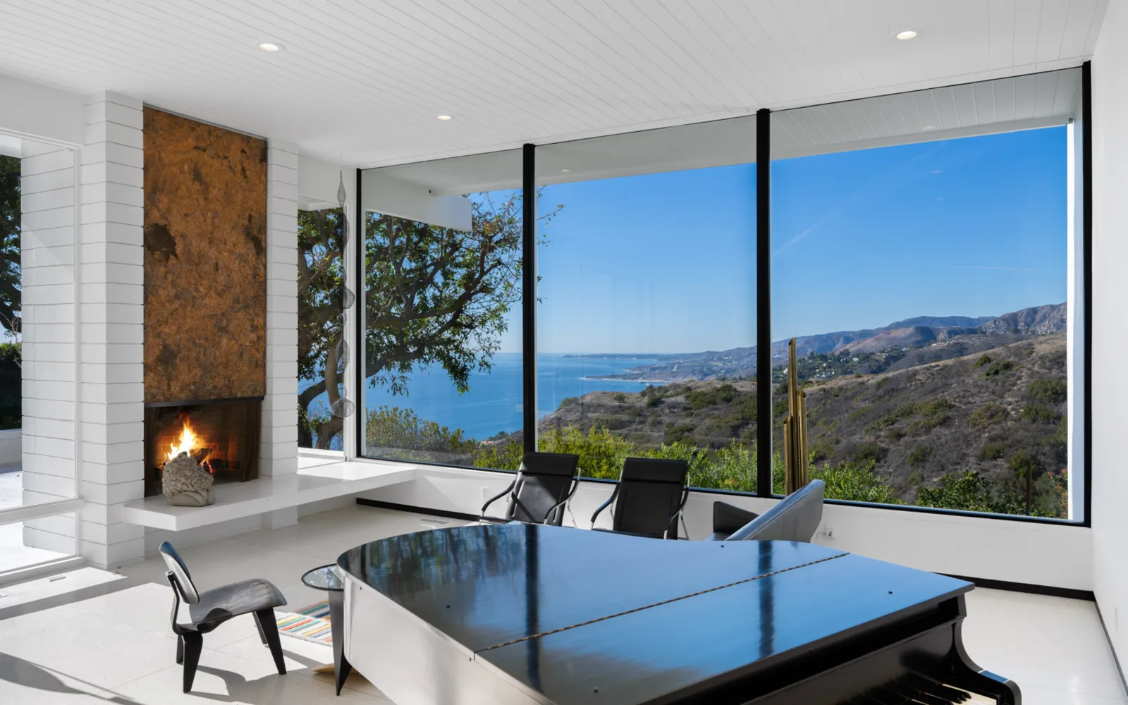 The living room at 20737 Cool Oak Way, Malibu: the fireplace and the ocean through the glass.