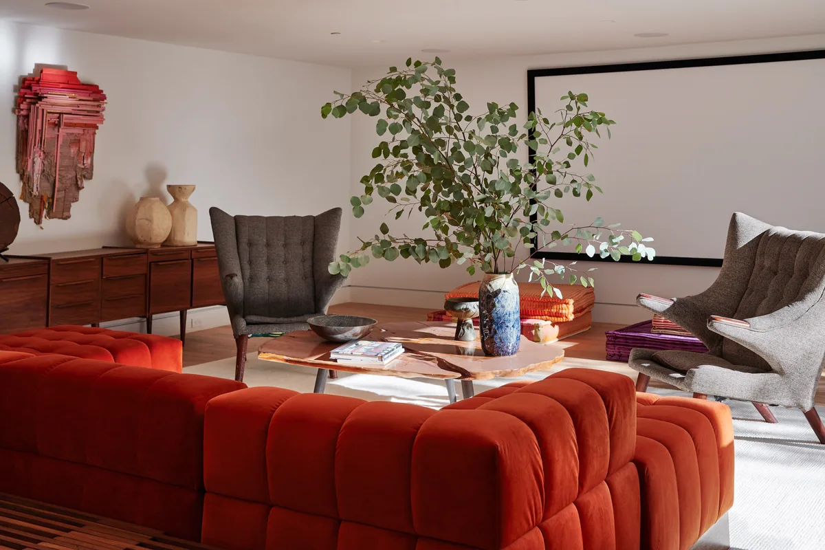 The media room at 1061 Loma Vista: an orange sofa, a wingback chair, art on the wall.