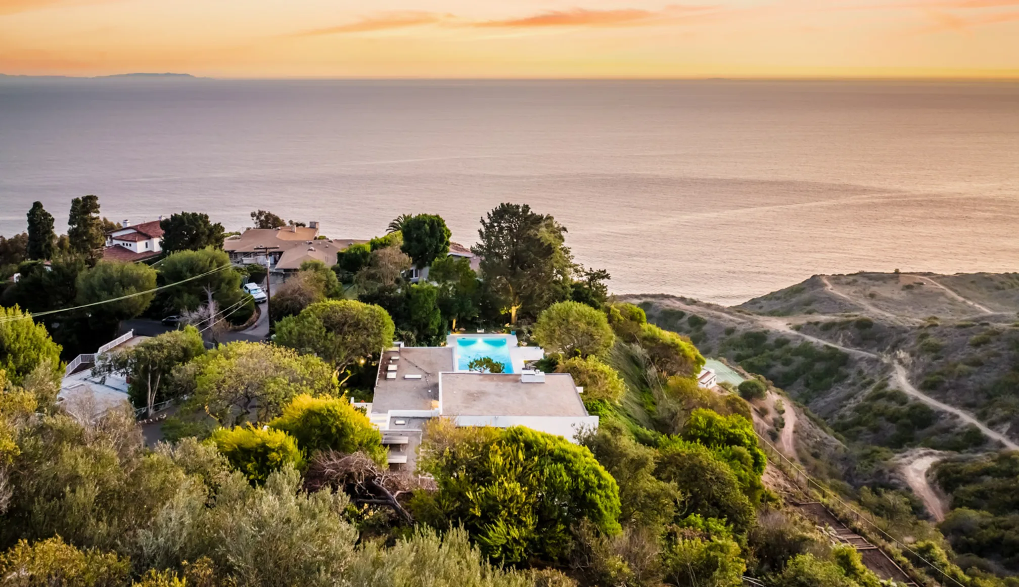 Cool Oak Way from the air at sunset: the house among its oaks, the coast and the Pacific beyond.