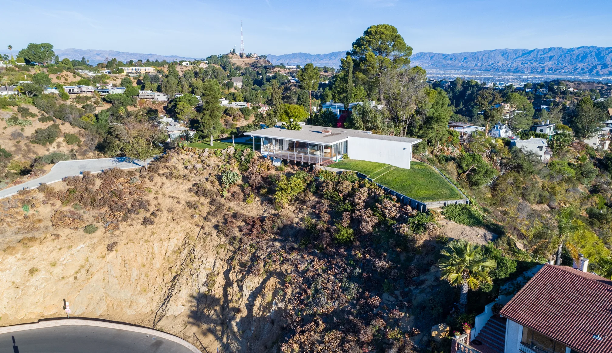 The Chuey House by Richard Neutra on its promontory above Los Angeles, the Hollywood Sign on the hill behind.